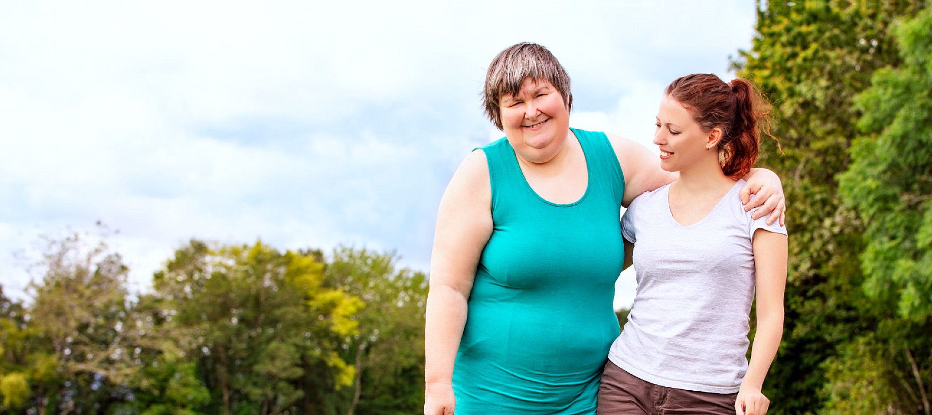 caregiver and a mentally disabled woman smiling at the camera